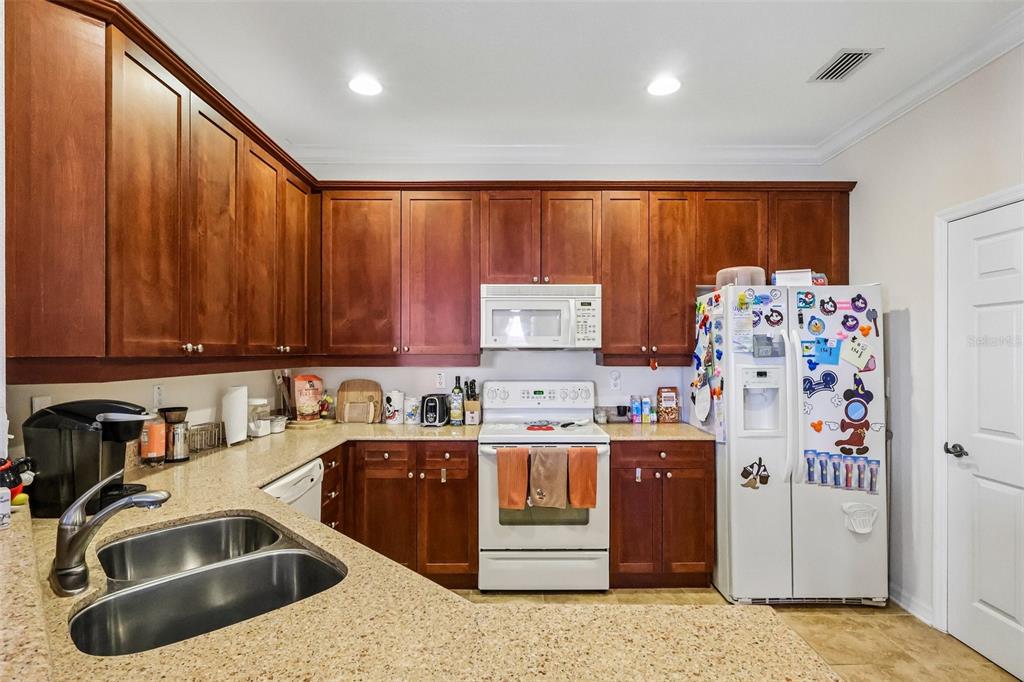 A kitchen features cherry wood cabinets, granite countertops, white appliances, and a double-basin sink — 8168 BOAT HOOK LOOP UNIT 303, WINDERMERE, FL