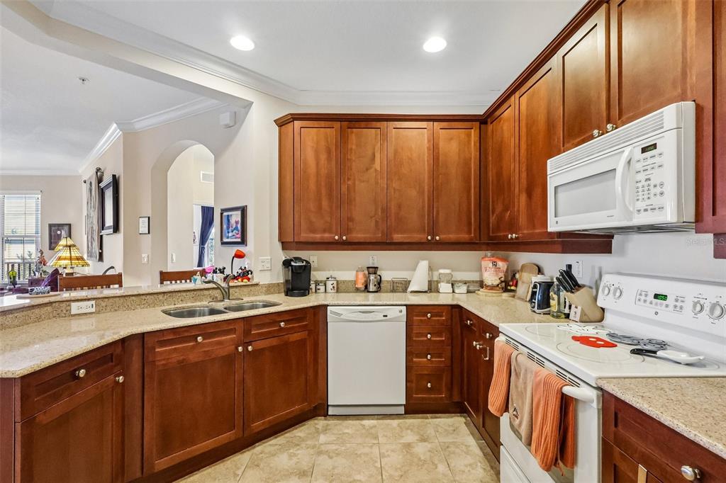 A kitchen features wood cabinets, granite countertops, a white dishwasher, and an over-the-range microwave — 8168 BOAT HOOK LOOP UNIT 303, WINDERMERE, FL