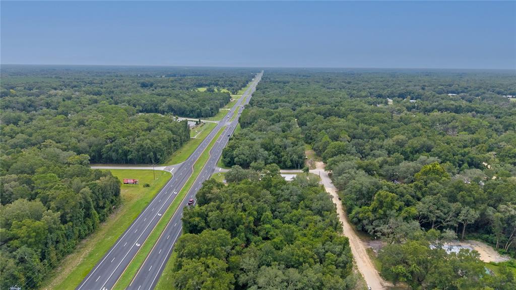 An aerial view shows a multi-lane highway running through a dense, wooded rural landscape — 0 N HWY 19, CHIEFLAND, FL