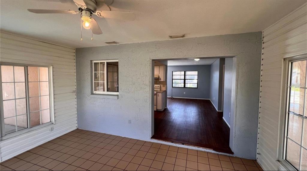 A sunroom with tile flooring and a ceiling fan opens into a living area — 9103 WHITMAN LANE, PORT RICHEY, FL