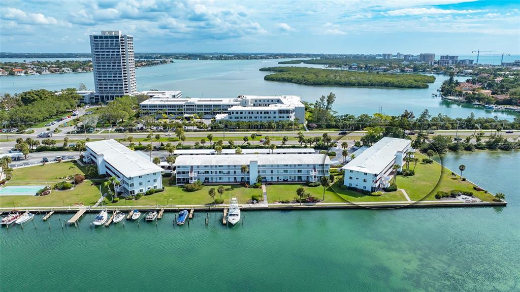 An aerial view shows waterfront condominium buildings with boat slips and a surrounding grassy area — 761 JOHN RINGLING BOULEVARD UNIT 5, SARASOTA, FL