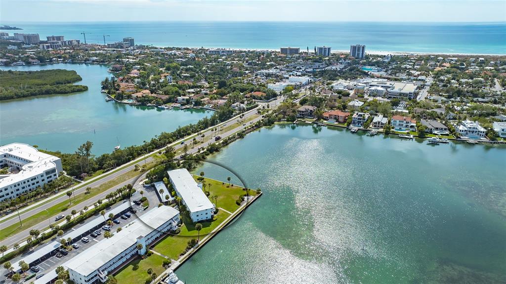 An aerial view shows a multi-story apartment complex situated on a waterfront peninsula — 761 JOHN RINGLING BOULEVARD UNIT 5, SARASOTA, FL