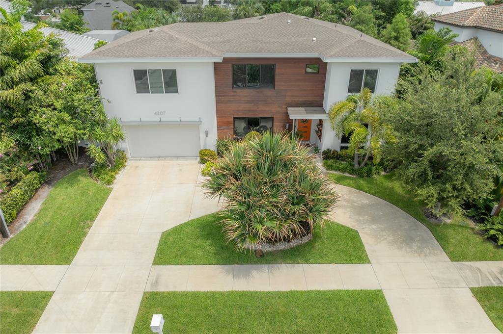 A two-story house with a wood-paneled facade, orange front door, and a concrete driveway — 4207 W JETTON AVENUE, TAMPA, FL