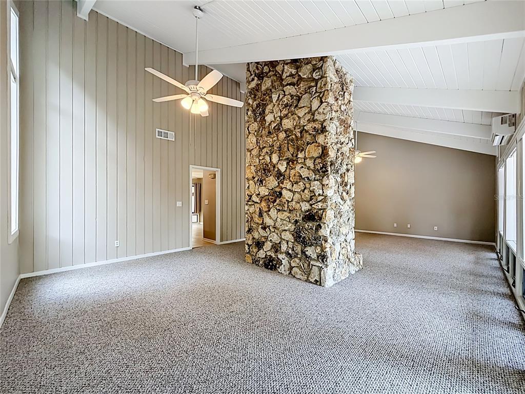 A living room features a large stone fireplace, vaulted ceilings, and wall-to-wall carpeting — 111 JUNIPER LANE, LONGWOOD, FL