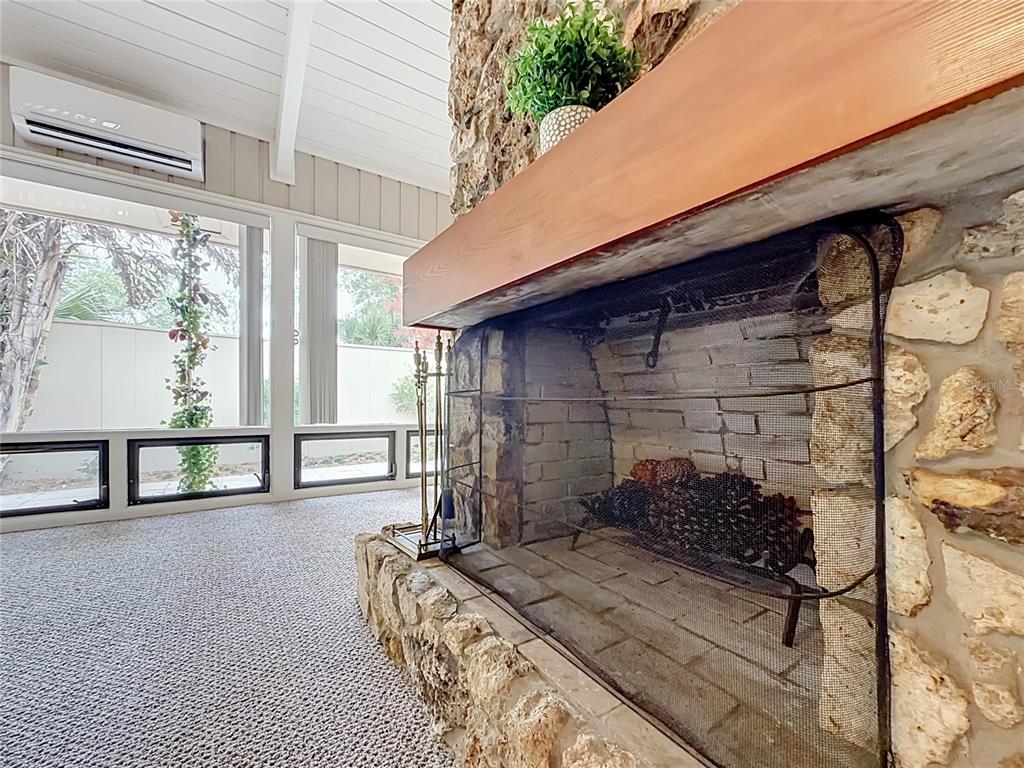 A stone fireplace with a wooden mantel sits in a room with carpeted flooring — 111 JUNIPER LANE, LONGWOOD, FL