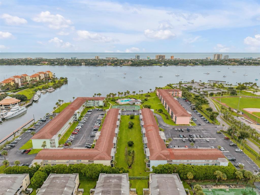 An aerial view shows multi-story apartment buildings with parking lots, a pool, and waterfront access — 715 S BEACH STREET UNIT 214D, DAYTONA BEACH, FL