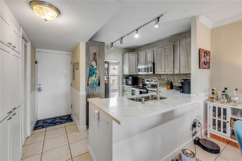 A kitchen with white cabinets, a marble-topped island, and a tiled floor near an entryway — 715 S BEACH STREET UNIT 214D, DAYTONA BEACH, FL