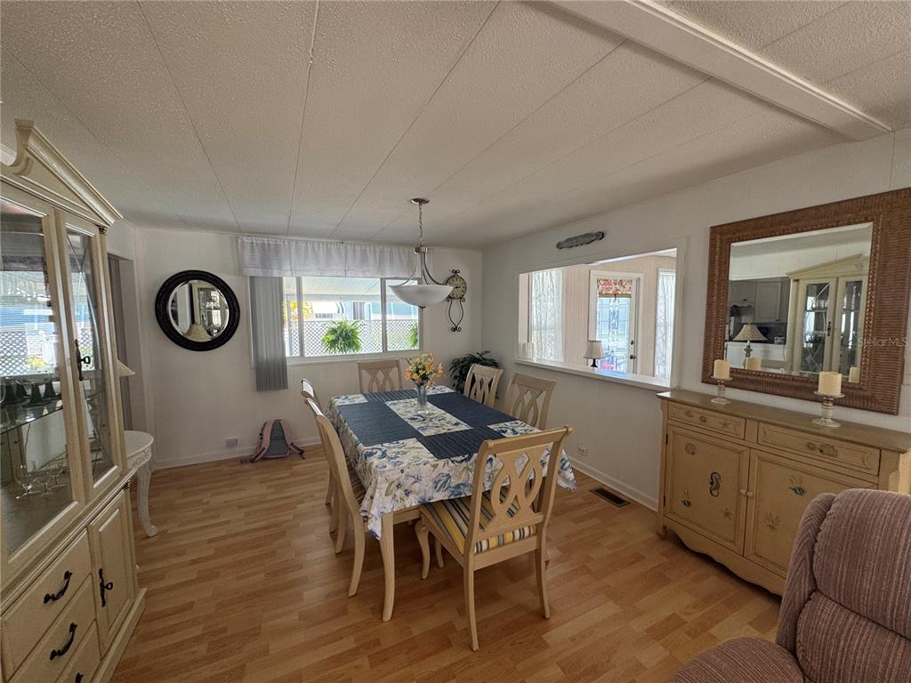 A dining room with a table, chairs, wood-look flooring, and a large wall mirror — 611 IRIS DRIVE, VENICE, FL
