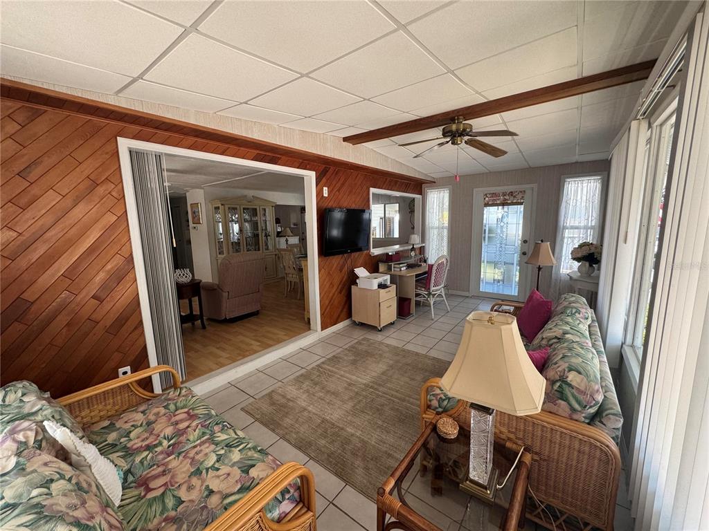 A sunroom features wood-paneled walls, tile flooring, a ceiling fan, and wicker furniture — 611 IRIS DRIVE, VENICE, FL