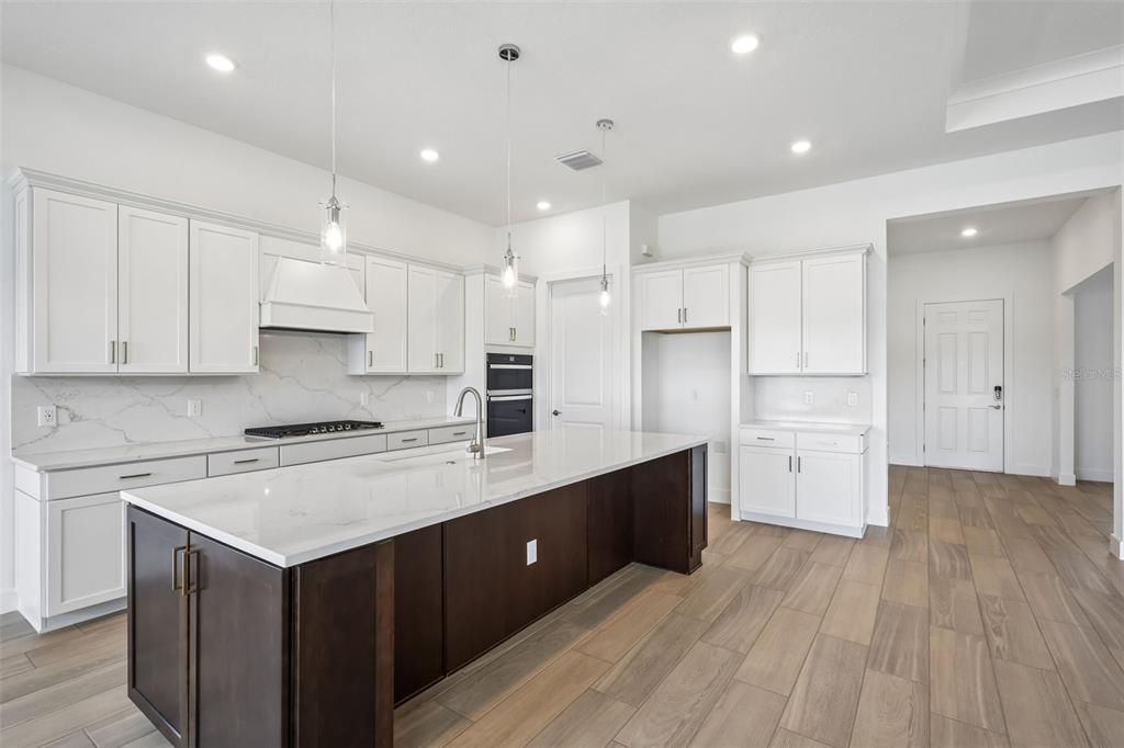 A kitchen with white cabinets and a dark wood island opens into a large room — 16694 HARVEST LEAF ROAD, SPRING HILL, FL