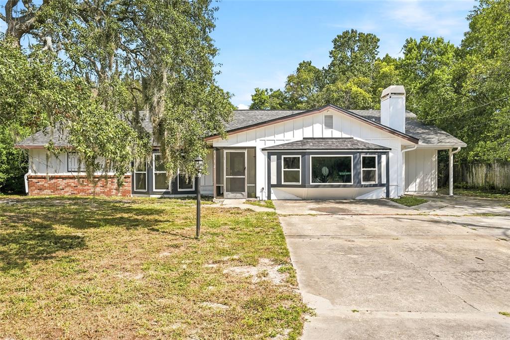 A single-story house with white siding, a brick base, and a large front bay window — 2112 MEADOW LARK ROAD, SPRING HILL, FL