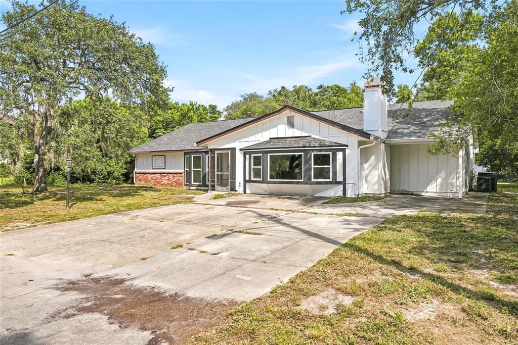 A single-story house with a white exterior, brick accents, a bay window, and a concrete driveway — 2112 MEADOW LARK ROAD, SPRING HILL, FL