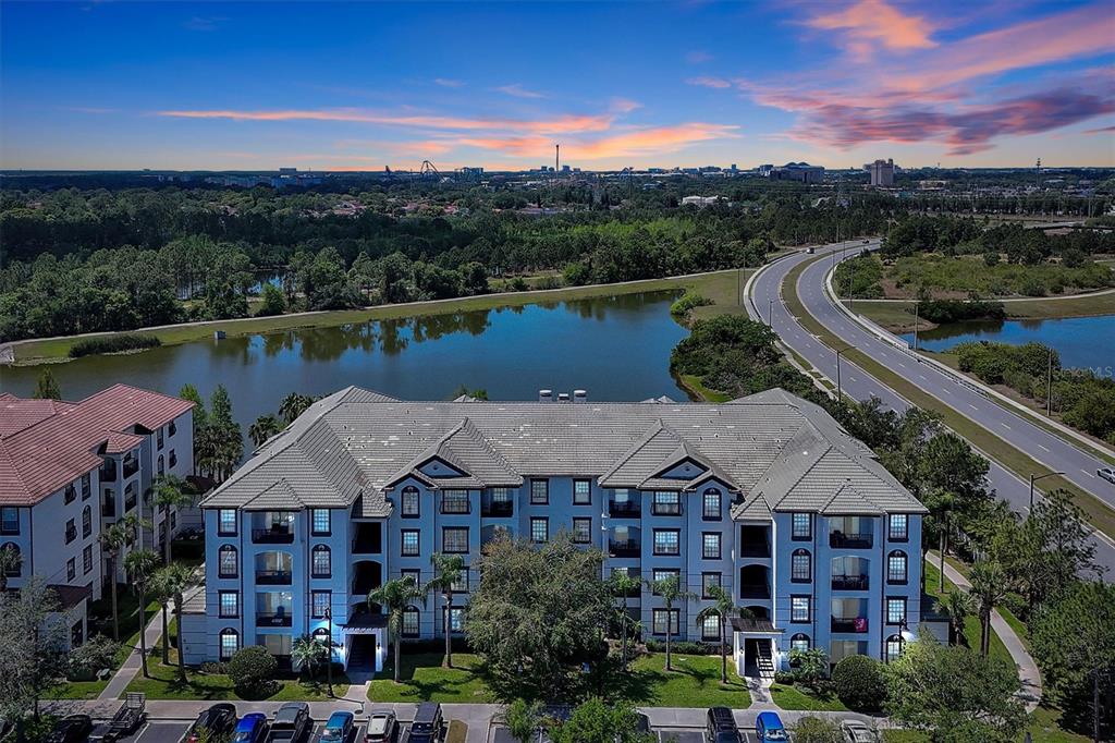 An aerial view shows a multi-story apartment building next to a lake and a road — 4126 BREAKVIEW DRIVE UNIT 30701, ORLANDO, FL