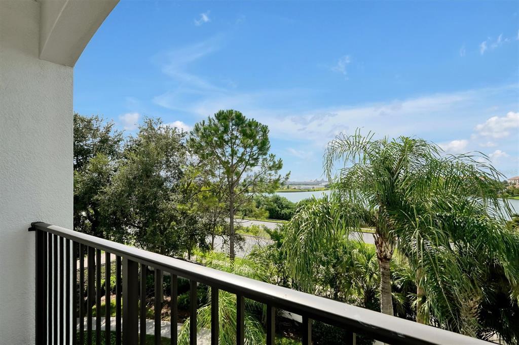 A balcony with a black metal railing overlooks a lake, trees, and a blue sky — 4126 BREAKVIEW DRIVE UNIT 30701, ORLANDO, FL