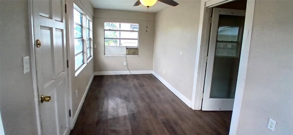 An empty room features wood-look flooring, a ceiling fan, and a window air conditioning unit — 2055 28TH AVENUE N, ST PETERSBURG, FL