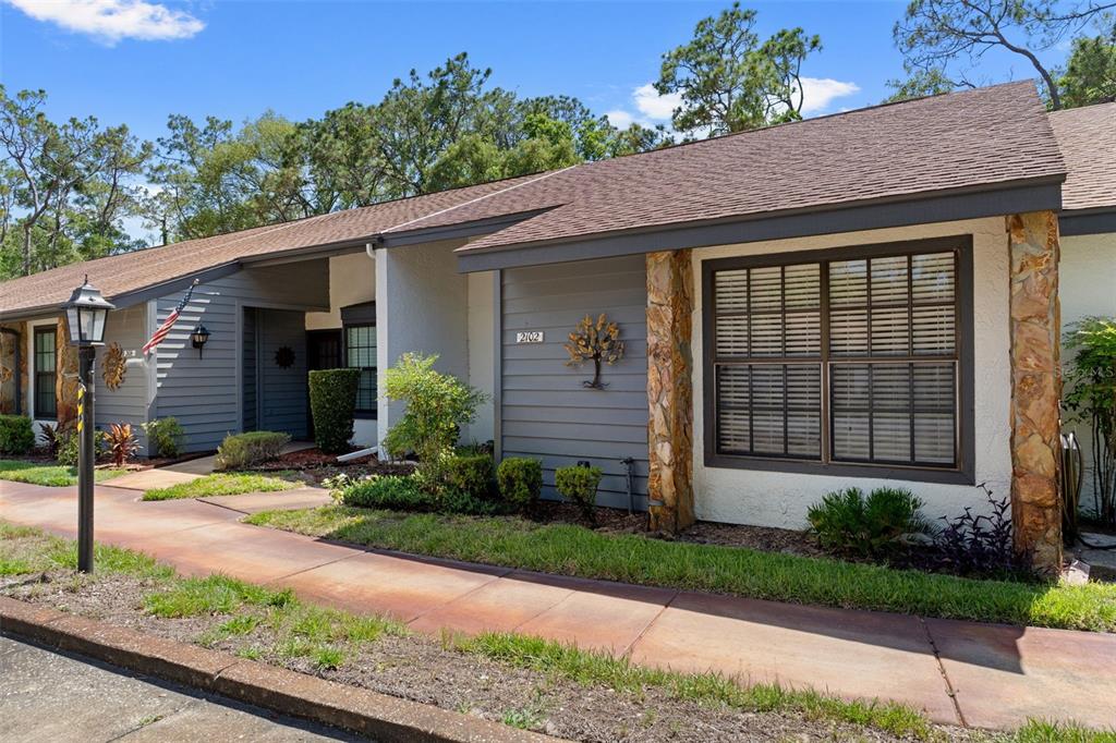 A single-story residence with gray siding, stone accents, and a sidewalk in front — 2102 FORESTER WAY, SPRING HILL, FL
