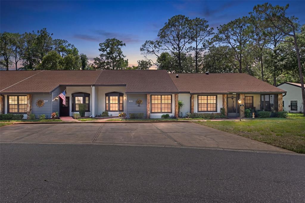 A single-story multi-unit residential building with a large concrete driveway and mature pine trees — 2102 FORESTER WAY, SPRING HILL, FL