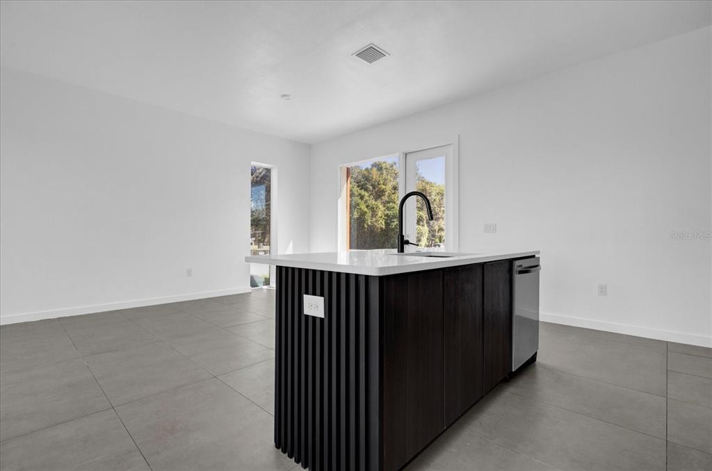 A modern kitchen island with a dark slatted base sits on gray tile flooring — 501 CHASTAIN ROAD, SEFFNER, FL