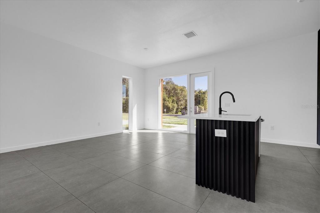 A modern kitchen with a black slatted island and large gray floor tiles — 501 CHASTAIN ROAD, SEFFNER, FL
