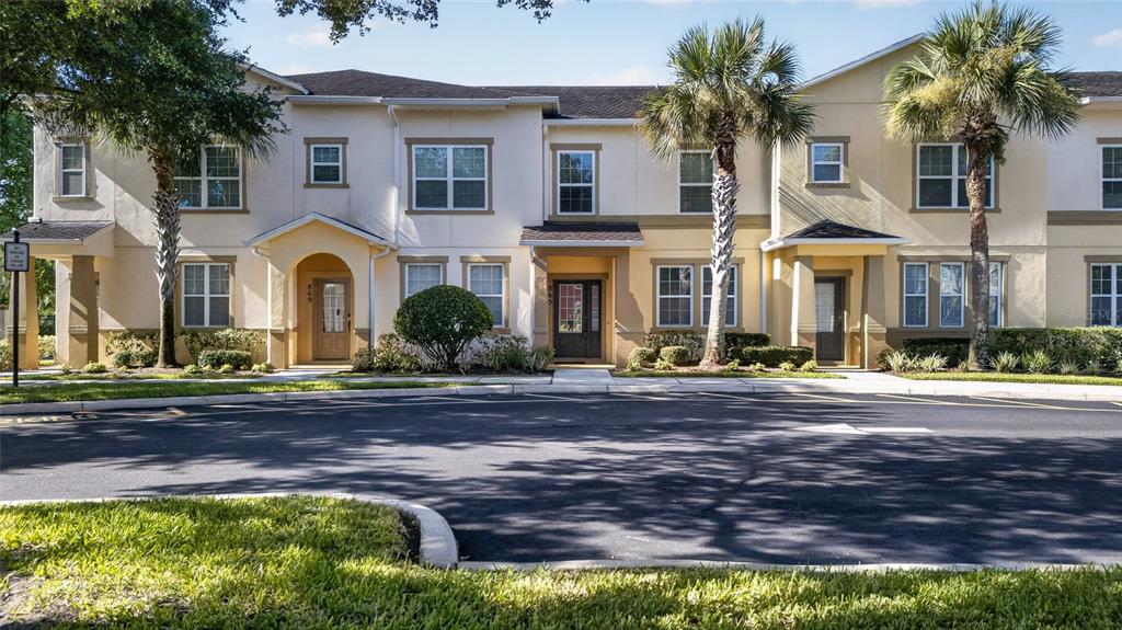A row of two-story townhomes with beige stucco siding and palm trees in front — 865 BELLES FERRY LOOP, SANFORD, FL