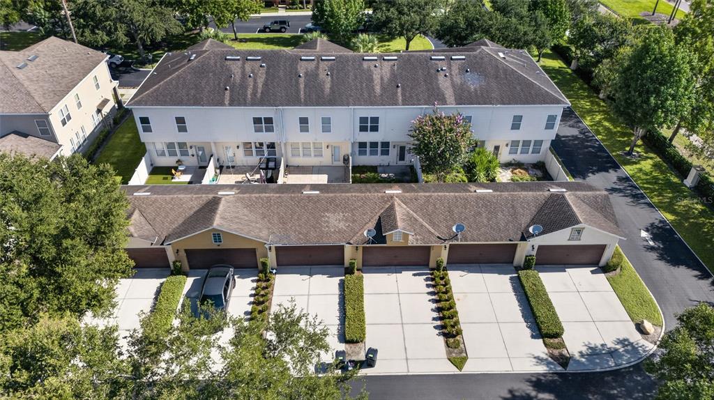 An aerial view shows a row of townhomes with attached garages and paved driveways — 865 BELLES FERRY LOOP, SANFORD, FL