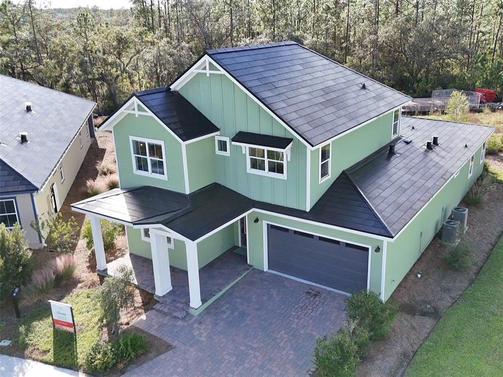 An aerial view of a two-story green house with a dark metal roof and garage — 6402 ROVER WAY, ST CLOUD, FL
