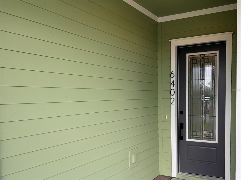 A front entryway features green horizontal siding and a dark door with a glass insert — 6402 ROVER WAY, ST CLOUD, FL