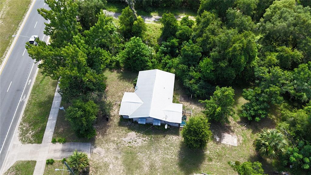 An aerial view shows a house with a white metal roof surrounded by dense trees — 1129 STATE ROAD 20, INTERLACHEN, FL