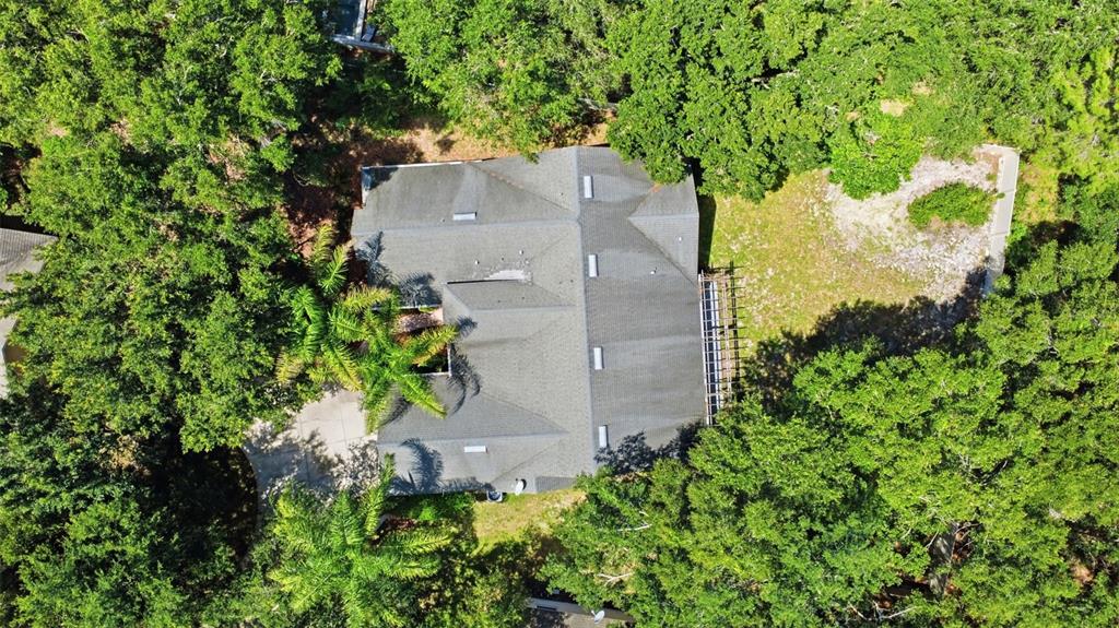 An aerial view shows a house with a gray shingled roof surrounded by dense trees — 1490 BENT OAKS BOULEVARD, DELAND, FL