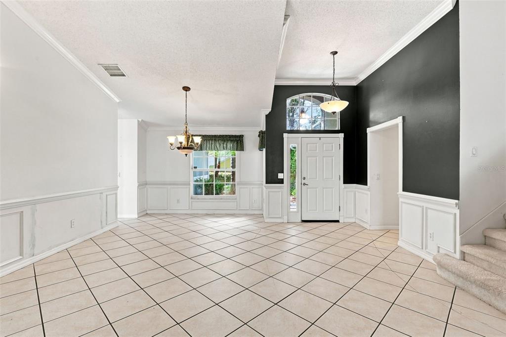 An empty room with white tile floors, wainscoting, a chandelier, and a black accent wall — 1490 BENT OAKS BOULEVARD, DELAND, FL