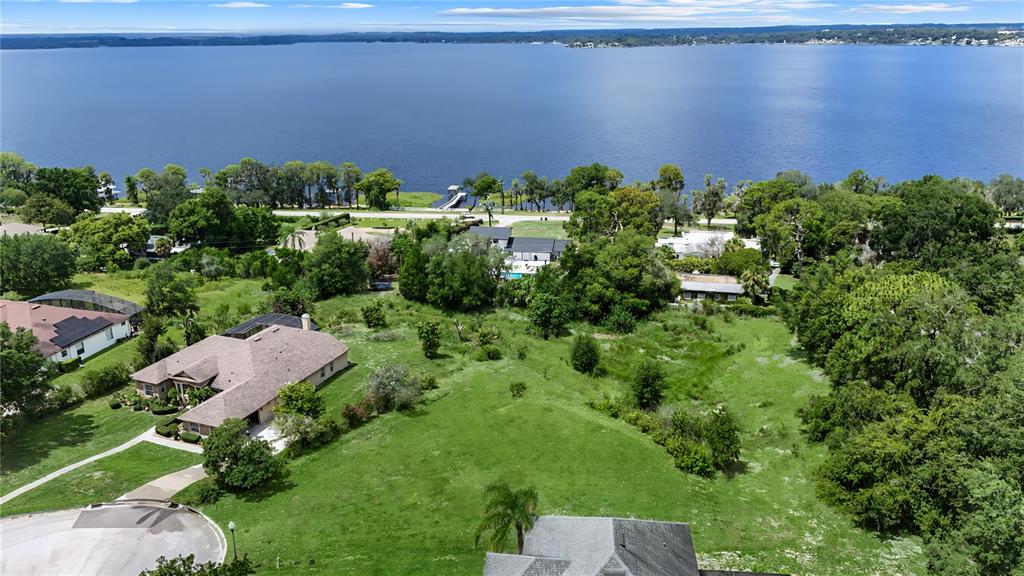 An aerial view shows a large grassy lot with houses near a lake — 12615 CROWN POINT CIRCLE, CLERMONT, FL
