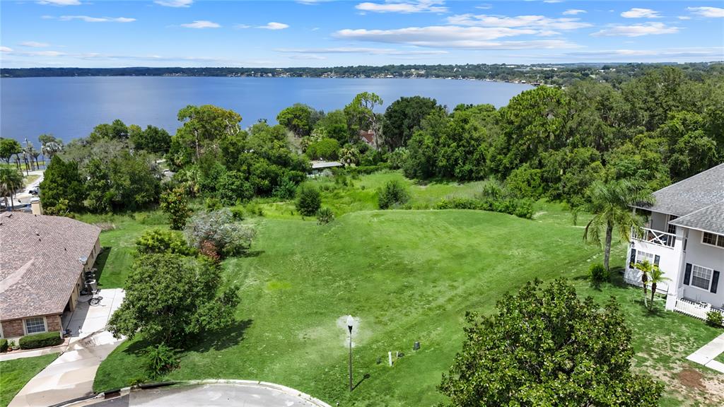 An aerial view shows a vacant grassy lot situated between two houses near a lake — 12615 CROWN POINT CIRCLE, CLERMONT, FL