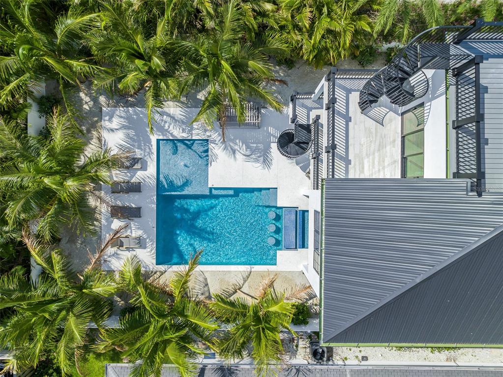An aerial view shows a swimming pool with a sun shelf and a spiral staircase — 128 FILLMORE DRIVE, SARASOTA, FL