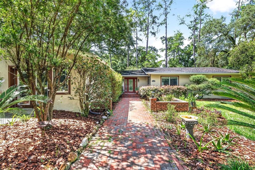 A brick walkway leads to the front entrance of a single-story house with landscaping — 11101 NW 12TH PLACE, GAINESVILLE, FL