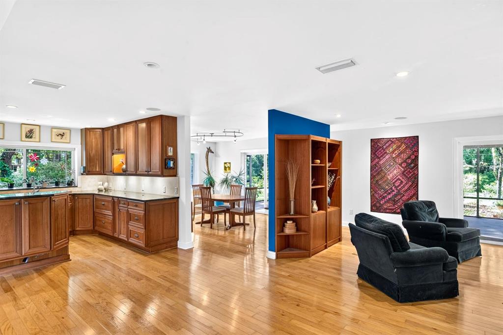 A kitchen features wood cabinets, a granite-topped island, and hardwood floors under recessed lighting — 11101 NW 12TH PLACE, GAINESVILLE, FL