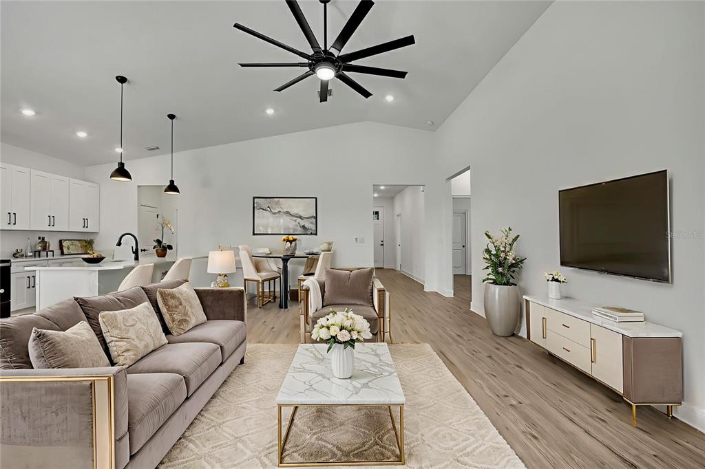 A modern open-concept living room features a gray sofa, marble coffee table, and ceiling fan — 13126 MEADOW SWALLOW AVENUE, BROOKSVILLE, FL