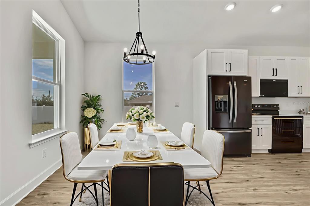 A dining area features a white table, modern chairs, a chandelier, and an adjacent kitchen — 13126 MEADOW SWALLOW AVENUE, BROOKSVILLE, FL