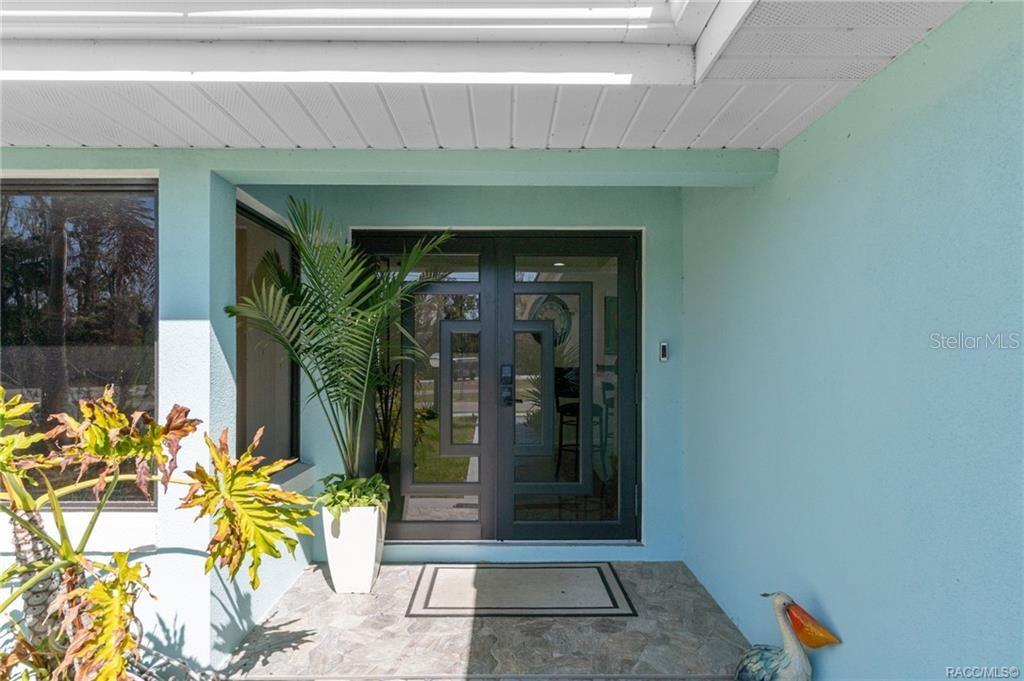 A light blue exterior wall features a dark gray double door with geometric glass panels — 171 SW 3RD STREET, CRYSTAL RIVER, FL