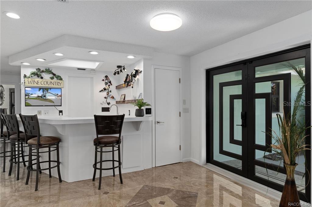 A white home bar with stools sits next to a black-framed glass double door — 171 SW 3RD STREET, CRYSTAL RIVER, FL