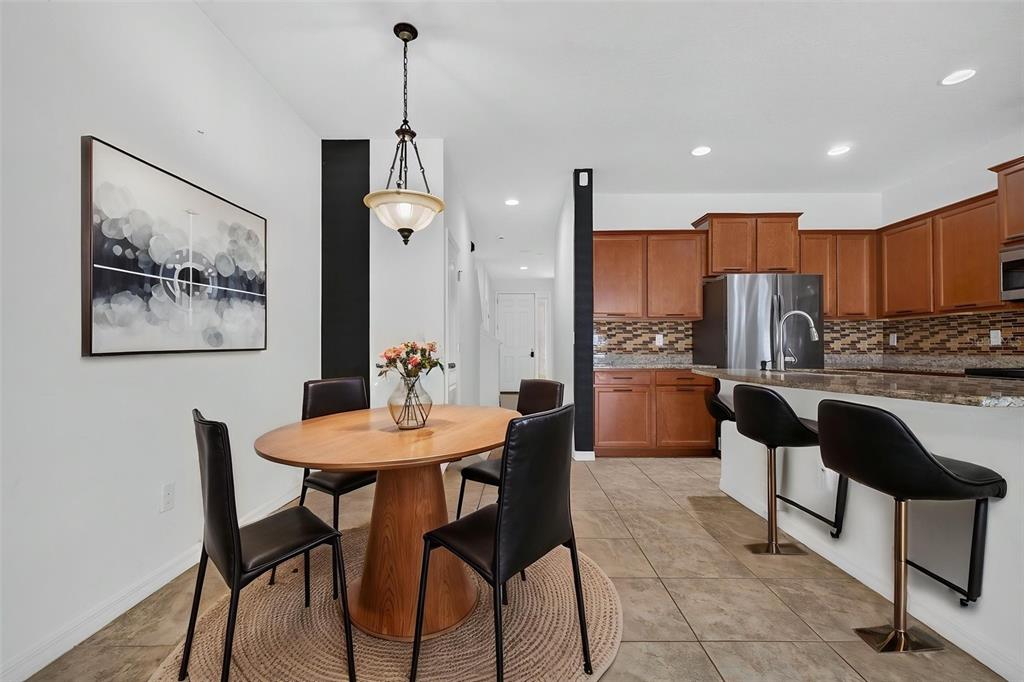 A dining area with a round wooden table sits adjacent to a kitchen with cabinets — 10406 ORCHID MIST COURT, RIVERVIEW, FL