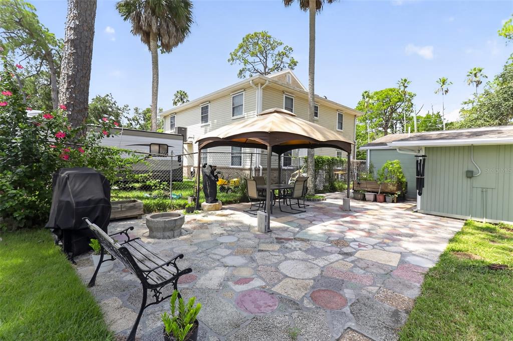 A backyard with a screened-in porch, a gazebo, palm trees, and a two-story house — 7212 WEDGEWOOD DRIVE, NEW PORT RICHEY, FL