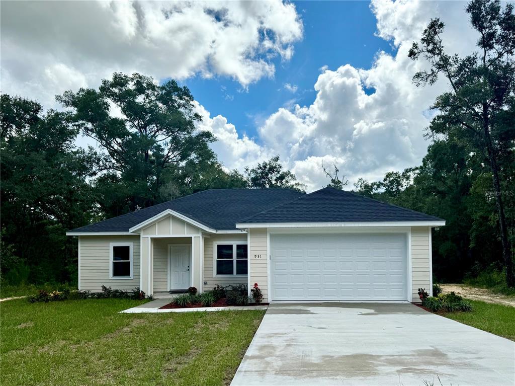 A single-story house with light yellow siding, a dark roof, and an attached two-car garage — 931 NE 154TH TERRACE, WILLISTON, FL
