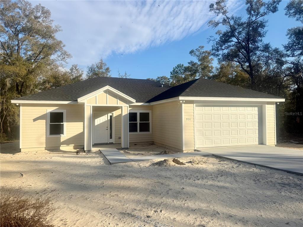 An open-concept kitchen and living area features gray wood-look flooring and a large chandelier — 931 NE 154TH TERRACE, WILLISTON, FL