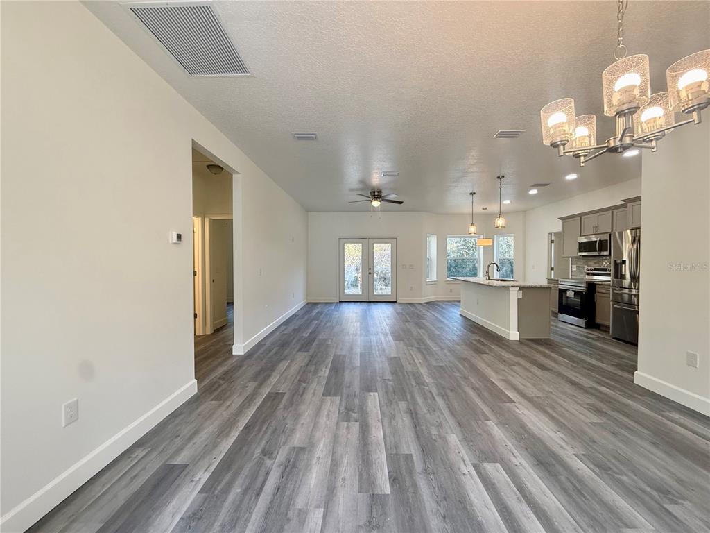 A dining area with gray wood-look flooring, a chandelier, and a large window — 931 NE 154TH TERRACE, WILLISTON, FL