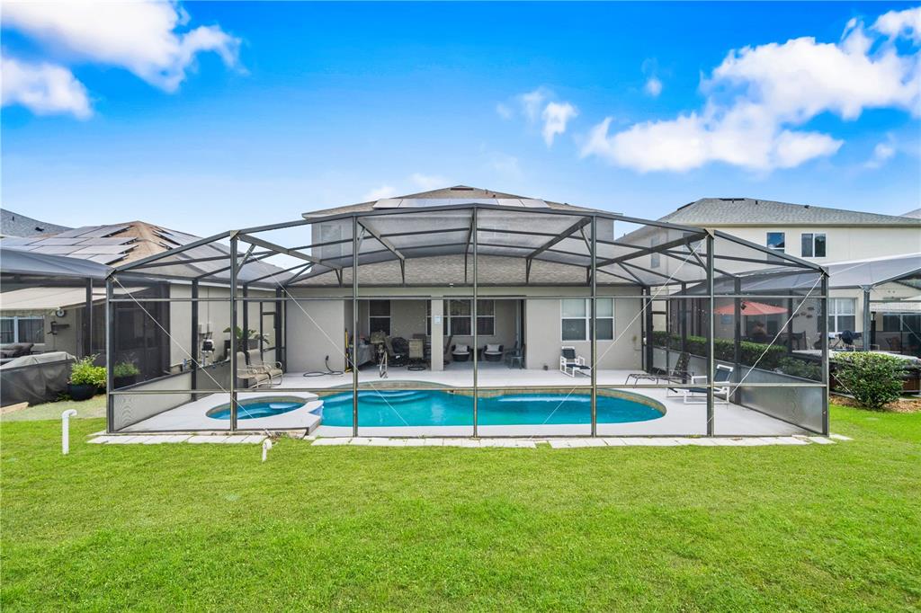 A backyard view of a two-story house featuring a screened-in pool and patio area — 1704 PINE RIDGE DRIVE, DAVENPORT, FL