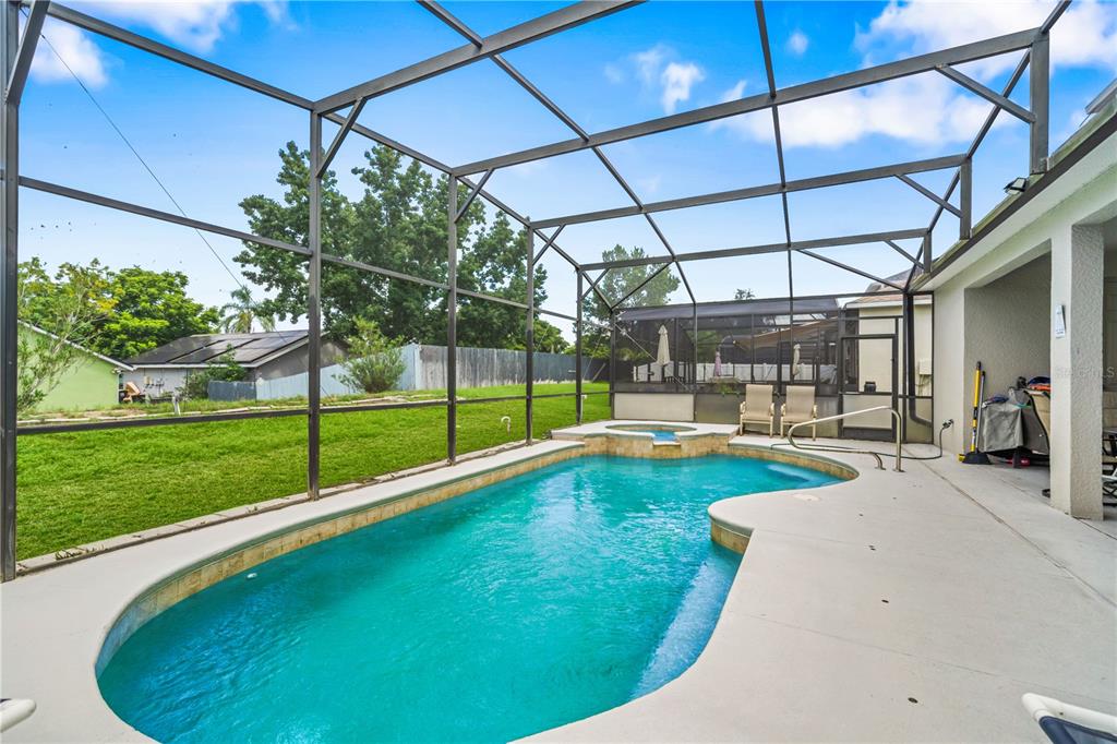 A swimming pool with an attached spa is enclosed within a screened-in patio area — 1704 PINE RIDGE DRIVE, DAVENPORT, FL