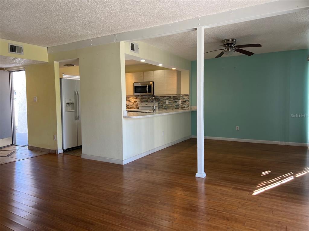 A living room with wood flooring, a ceiling fan, and an open kitchen with a counter — 2625 STATE ROAD 590 UNIT 2514, CLEARWATER, FL