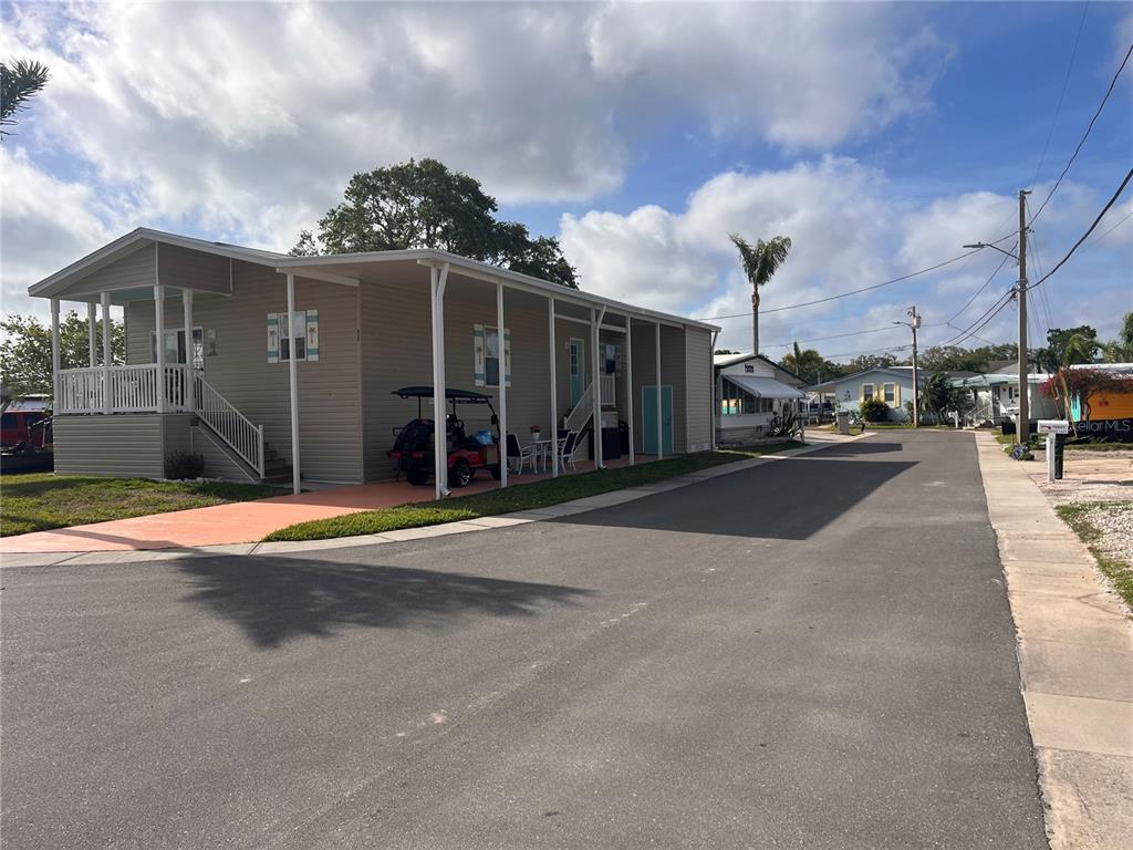 A light-colored manufactured home features a covered carport, a front porch, and a paved driveway — 105 SCHOONER DRIVE UNIT 105, PALM HARBOR, FL