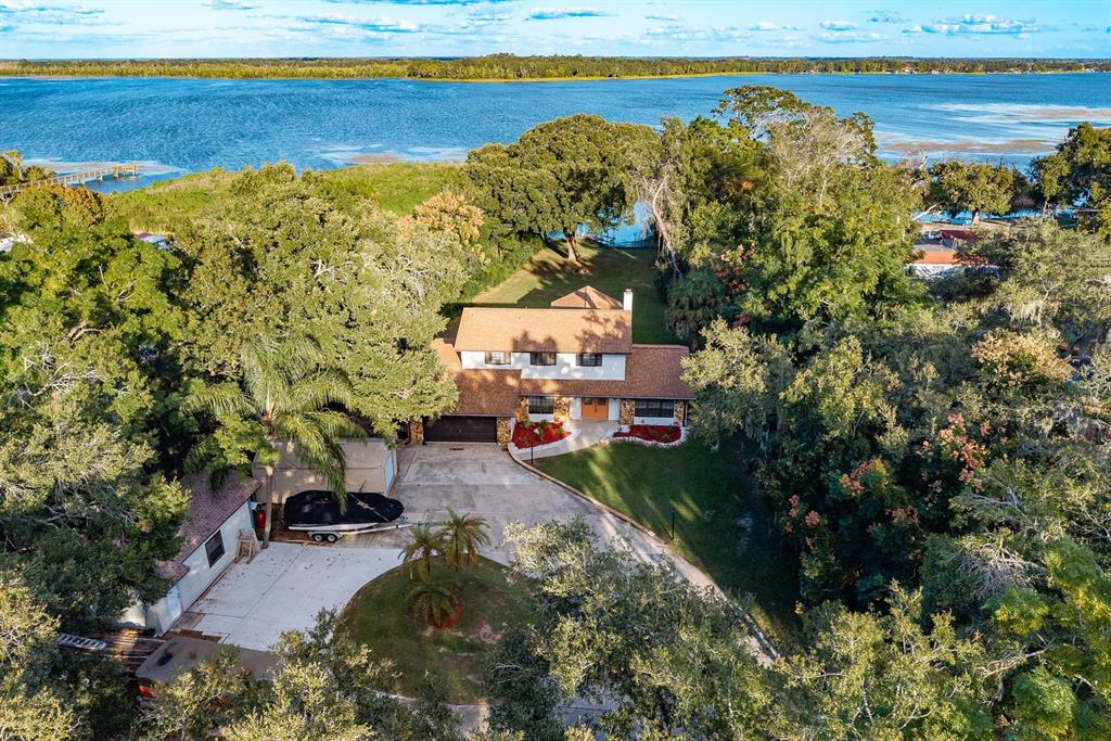 A two-story house with a stone facade, brown roof, and attached garage at sunset — 1416 GROVE AVENUE, LEESBURG, FL