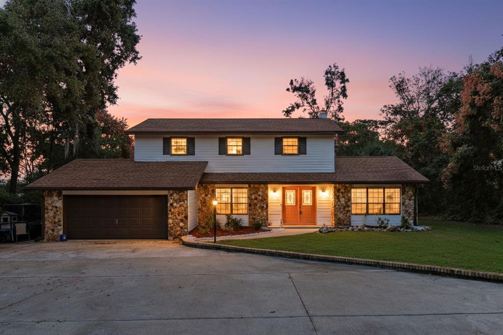 A two-story house with a stone facade, orange double doors, and an attached garage — 1416 GROVE AVENUE, LEESBURG, FL